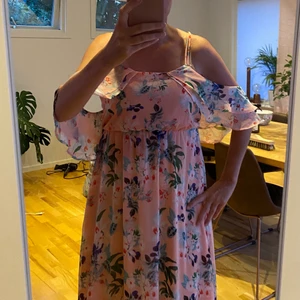 Långklänning  - Fin långklänning i skirt material. Rosa med blommor. Tunna axelband. Knapp i ryggen. Löst hängande tyg som vilar på armarna. Storlek S. Betalning via swish. Köparen står för frakten. Kan skicka spårbart om man önskar. 