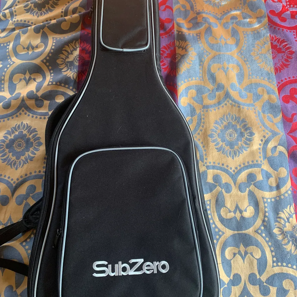Svart gitarrfodral från SubZero. Fodralet är 108cm långt, kan bäras som en ryggsäck och har inga defekter.. Väskor.