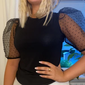 Festlig topp - Tröjan har en fin passform med stora puffärmar i ett genomskinligt svart tyg