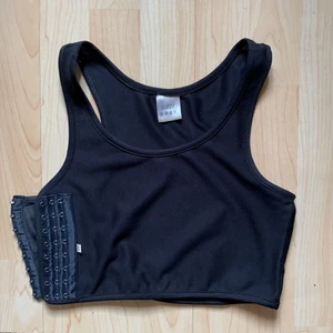 Chest binder i svart färg - En chest binder som använts för cosplay bruk men köparen för använda plagget hur de vill. Den är mycket elastisk, andningsbar och enkel att använda. Går att justera spänningen i tre nivåer. 
