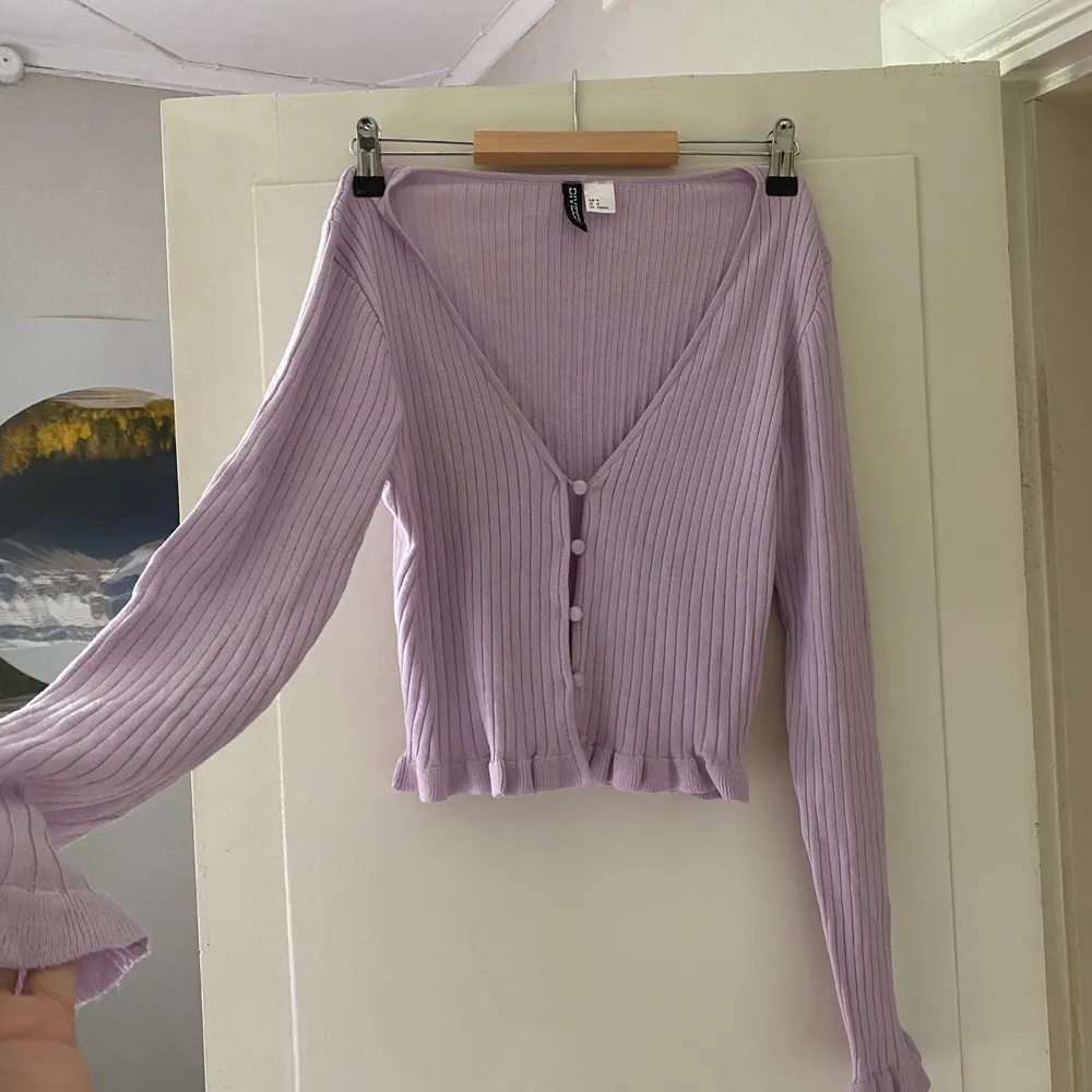 En söt rosalila knapptopp med volanger längs ärmarna och slutet på tröjan. Helt oanvänd, köpt från H&M💓. Toppar.