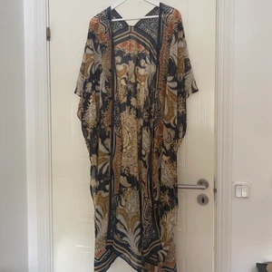 Mönstrad kaftan  - Svart/orange Mönstrad kaftan från h&m! Knappar framtid för att förlusta kaftanen! Onesize! Använd under 1 semster! Frakt ingår i priset!