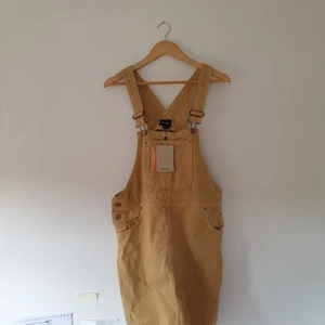 Hängselklänning - Supersöt typ senapsgul hängselklänning i jeanstyg från Monki som tyvärr aldrig blivit använd. Behöver ett nytt hem 🌟