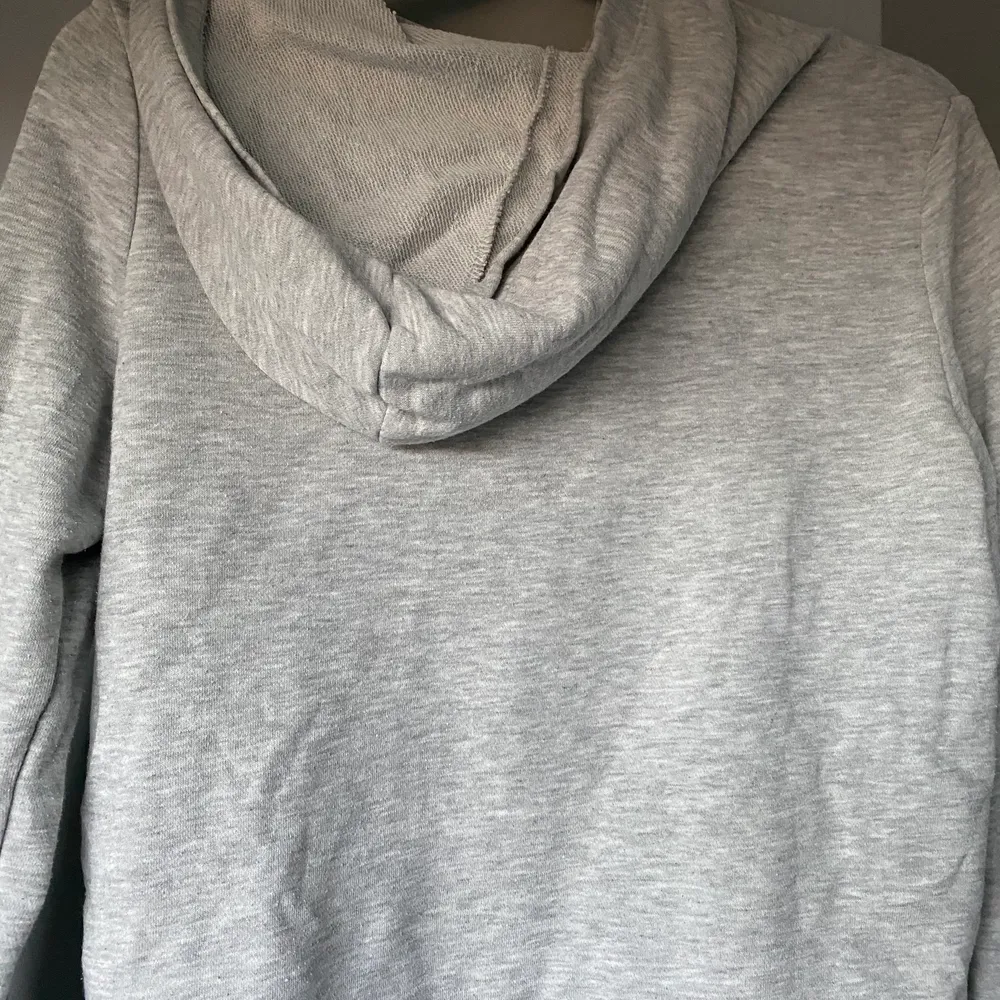 Säljer denna snygga gråa hoodie som tyvärr börjat bli för liten och där av inte används lika ofta. Den har en liten röd fläck från en white board tavla penna (se tredje bilden), vid köp kan jag självklart få bort den om det går. Kom med egna prisförslag!. Hoodies.