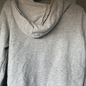 Grå hoodie - Säljer denna snygga gråa hoodie som tyvärr börjat bli för liten och där av inte används lika ofta. Den har en liten röd fläck från en white board tavla penna (se tredje bilden), vid köp kan jag självklart få bort den om det går. Kom med egna prisförslag!