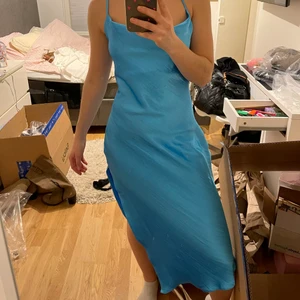 Blå satin klänning - Helt ny, mellan lång blå satin klänning med slits på ena sidan och fin snörning i ryggen. Älskar den men kommer inte till användning så säljer den vidare💙
