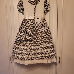 Festklänning Helt ny! - Söt festklänning med tre underkjol för volym. Helt ny! Jag har svårt att bedöma storleken, kanske flicka i 9 års ålder? Midjan ca. 58 cm. Liten tillhörande väska i samma tyg som klänningen. 