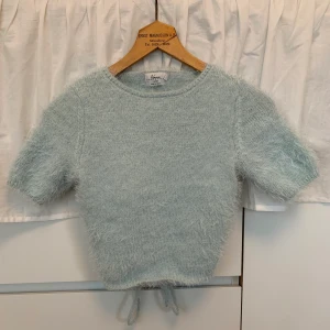 Croppad topp med öppen rygg - Ljusblå croppad topp med öppen rygg från en av Hanna Schönbergs kollektioner med NAKD. Stickad i ett ”fluffigare” material. Stl xs (passar också S). 