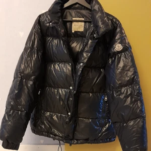 Moncler jacka (lite fel) - Säljer jackan då den har några fel. Jackan är original och jag kan skicka fler bilder på alla detaljer. Dragkedje"hållaren" har gått av, men funkar att öppna och stänga utan några problem. Och innanför jackan där seriebilden ska vara, är tyvärr borta. Dragkedjan på vänster ficka funkar, men går ur spår om man drar till botten hårt. Dragkedjorna går att fixa om man går till en skräddare. Jackan i sig är väldigt fin. Kan skicka fler bilder, så ni ser att jackan är original. Skriv on ni har frågor.