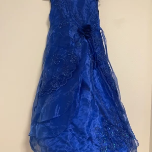 Blå barnklänning  - Blå festklänning för barn, kan passa upp till 12 år. Oanvänd. Frakten ingår i priset. Möter inte upp. Väldigt fin och elegant. Nypris 1800. 