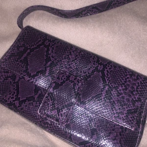 väska - väska med snake print i lila, oanvänd. frakten kan väljas spårbar om man vill.