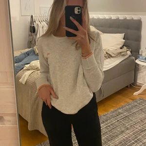 Sweatshirt från Only - Säljer denna gråa sweatshirt med lite korallrosa detaljer ifrån Only i storlek S. Superfin och i bra skick, men som bara inte kommit till användning. Säljer den för 50kr😊