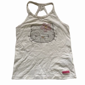 Söt y2k hello kitty topp.  - Super söt hello kitty topp med annorlunda band i ryggen (se bild 2). Alla kristaller är kvar! Köpt på H&M vid 2000-tal, så finns inte kvar längre. Perfekt för sommaren! Barnstorlek 104 men funkar för mig som har S och XS! Har endast gått upp lite i tråd vid ärm bandet men inget som syns! Köparen står för frakten! Kolla in mina andra plagg då jag gärna samfraktar! ❤️🥰 Buda privat eller i kommentarerna! 
