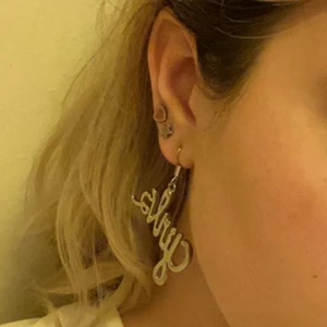 Örhängen - Girls - Coola örhängen med texten ”girls”. Vet inte var de är ifrån då jag fått de. Helt oanvända förutom till bilden. Materialet är okänt men de är silverfärgade.