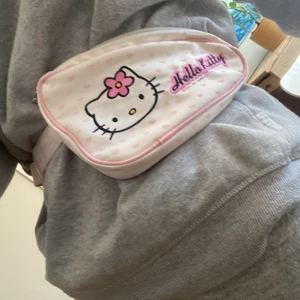Y2K fannypack  - En fannypack från tidigt 2000-tal i Hello-Kitty stil. Min syrras gamla blöjväska men mobil och andra tillhörigheter passar lika till det. En svag våtservettsfdoft men inget som sänker kvaliten! Bra skick inte mycket använd! Buda! INGA SKAMBUD. Säljer endast vid bra bud