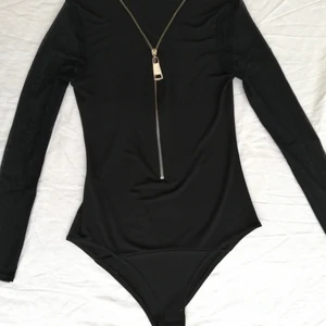 Svart body med dragkedja  - Säljer svart body med fungerade dragkedja. Bodyn är i fint skick men jag fick den i andra hand så jag vet inte vart den kommer ifrån. Man kan se knäppt på andra bilden och det lite genomskinlig tyget som är på ärmarna på tredje bilden. 