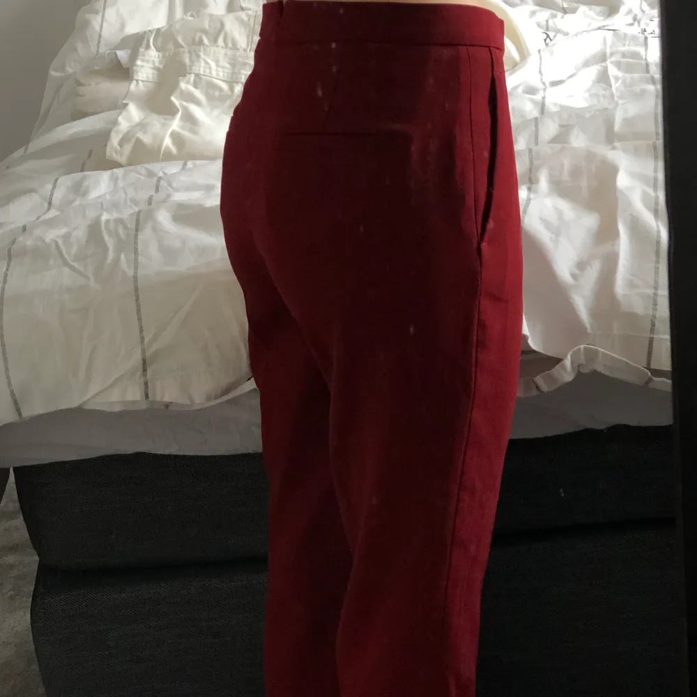 Vinröda kostymbyxor i en utsvängd modell. Lågmidjadd, storlek xs. Dom är uppsydda men är bra längd på mig som är 163cm.. Jeans & Byxor.