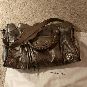 Balenciaga väska  - Intressekoll på min unika guldiga balenciaga city bag! Finns definitivt tecken på användning men tycker nästan enbart att det bidrar till en cool effekt, är väl en smaksak. Är pågrund av slitaget villig att släppa den för ett relativt billigt pris. Skriv vid frågor eller önskan om fler bilder! 💕 Äkthetsbevis finns! Väskan är 37x24cm