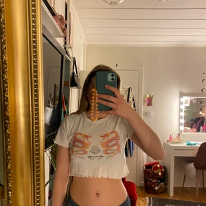 Croppad t-shirt 🧡❤️🧡 - Jättefin croppad vit t-shirt med drakar och volang i ärmarna och längst ner på tröjan. Jättefin och i bra skick. 🧡❤️🧡❤️
