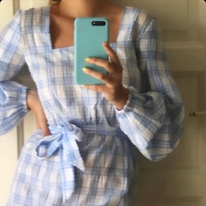 Sommarklänning - Blå vit rutig sommarklänning ifrån NAKD. Säljer pga den inte användes så som jag önskade förra sommaren. Supersöt med rosett att knyta kring midjan. Strl 34 men sitter bra på mig som är S