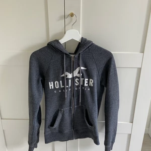Hollister hoodie, mörkgrå - Hoodie med dragkedja från hollister, storlek xs. Fint skick men säljer pga att jag inte använder den längre😇 nypris är ca 600 kr