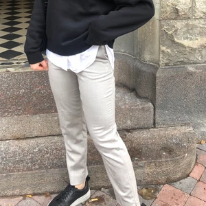 Kostymbyxor  - Superfina grå/beiga kostymbyxor från HM i storlek 34. De är bara använda 2 gånger och är därför i väldigt fint skick. De har en medelhög midja som slutar precis under naveln. Jag är 160 cm lång och de går precis ner till anklarna på mig💓💓 Köparen står för frakten!! 