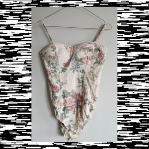 Body med definierad byst - Blommig body med definierade kupor så lite bustier/korsett liknande. Perfekt i längd för mig som är 170 cm. Otroligt fin och fint skick 🌸