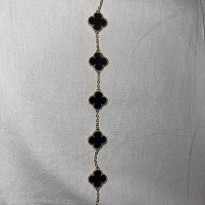 Armband  - Guldfärgat armband med svarta klöver på, använd vid 1 tillfälle