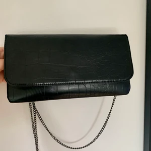 Kuvertväska/ svart festväska/ fint skick/ clutch  - Svart kuvertväska i toppskick. Rymmer det viktigaste. Väskan har ett innerfack med dragkedja. Mått: 27 x 15 cm.