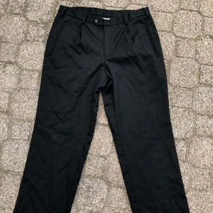 Svarta kostymbyxor - Svarta kostymbyxor köpta second hand. Bred passform. Det står inga storlekar eller så på byxorna men inner- och midjesömmen är respektive 77 och 94 cm. Priset inkluderar inte frakten. Tar swish.