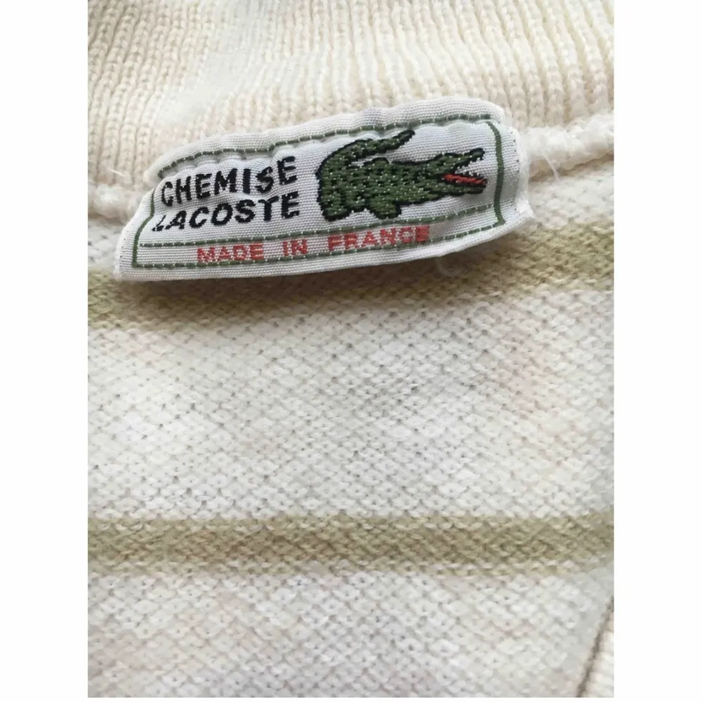 Vintage Lacoste v-ringad tenniströja / stickad tröja. Ecru vit med khaki ränder. Ull-blandning. Mycket bra vintage skick, har använts men inga uppenbara defekter. Troligen från 70-talet! Köpt i Italien. Passar XXS-S kvinnor eller XXS-XS man.. Stickat.