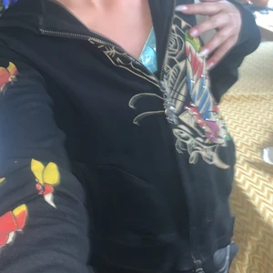 ed hardy 😍🔫 - Skitcool svart ed hardy med en fjäril på som är köpt här på plick! Fint skick! Säljer då jag behöver pengar och jag använder den inte så mycket! På vänstra ärmen är en ros och på högra är det massa fjärilar. Baksidan är det en stor och några små fjärilar och texten ”love”, framsidan har bara en stor fjäril med rhinestones / diamanter och i vänstra hörnet typ så står det ”ed hardy eternal”! Luvan har en fjäril med ögon. Det står ingen storlek men skulle säga xs till liten m❤️KOM MED EGNA PRISFÖRSLAG❤️