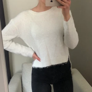 Tröja - Vit tröja/kofta i jättemjukt ”fluffigt” material med en liten slitis i sidan (se andra bilden). Passar XS/S. Helt onavänd med prislapp kvar. Ordinarie pris 249.