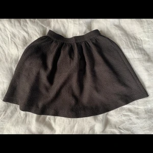 Kort kjol med textur - Väldigt söt kjol i en kort utsväng modell med textur från Monki. Måttligt använd och i väldigt fint skick. Storlek 34. Köpare står för frakt.