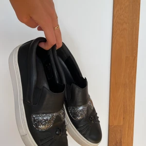 Karl Lagerfeldt slip-ons - Coola och unika sneakers från Karl Lagerfeldt. 100% läder och allmänt riktigt bra kvalité. Har inte fått ut så mycket användning som jag hoppades på då de är lite för små för mig tyvärr. Använd men gott skick. Strl 37 men funkar även de med en liten strl 38! Frakt ingår i priset.