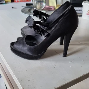 Bianco Footwear svarta pumps - Svarta pumps med 11 cm höga klackar. Rosetter framöver fotdelen, öppna i tån. Använda men i bra skick.
