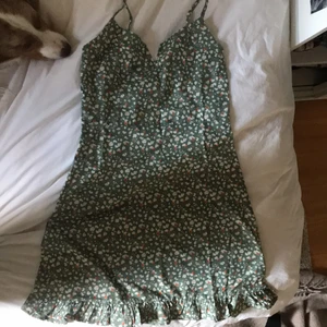 Grön blommig klänning från shein - Helt oanvänd klänning från shein i storlek S, grön med blommor, figurnära runt midjan, ”hård” vringning där fram. Justerbara band och med en dragkedja i sidan💕