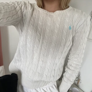 Tröja från Ralph Lauren - Vit kabelstickad tröja från Ralph Lauren med ljusblått märke. Storlek L i barnstorlek så skulle säga att det är en vanlig xs. Köparen står för eventuell frakt. 