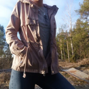 Vårjacka från H&M storlek S - Fin vårjacka från H&M i en smutsrosa färg. Storlek S. Superskön till våren när man gärna vill ha en lite tunnare jacka. Snörena som hänger på sidorna går att dra ut om man vill markera midjan ännu mer. 