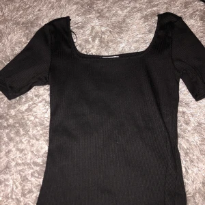 Ribbad tshirt  - Svart ribbad tshirt med utgivning i både fram och bak. Aldrig använd pga att den va för liten 