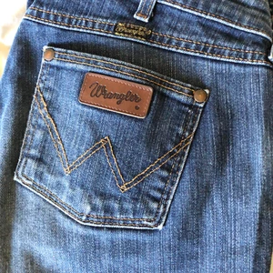 Wrangler bootcut jeans - Wrangler bootcut jeans med cool slitning och låg midja. Står storlek 32x32 i dem men passar kanske någon som vanligtvis har S/M. Dom sitter bra på mig som har S bortsett från att dom är lite stora i midjan. 