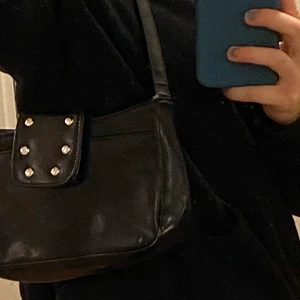 Svart trendig väska - Säljer denna superfina trendiga väskan som är köpt på humana, man får plats med det viktigaste i den (plus det är många fack), i jättefint skick men kommer tyvärr inte till användning.