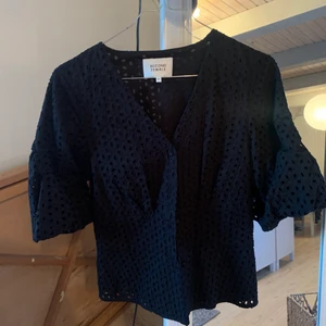 Svart Blues/top med knappar XS - Blues/top från märket Second Female i strl XS. I fint material/mönster, lite puffiga armar och sitter fint i midjan. 