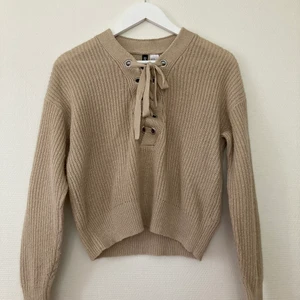  Beige stickad tröja  - En beige stickad tröja från H&M. Man kan justera vringningen med banden.