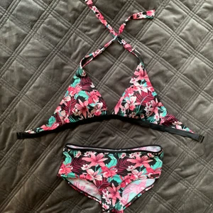 Rosa Bikini - Rosa, blommigt bikiniset. Toppen passar bra på mig som är 80C. Botten delen sitter bra/lite för stor på mig som är M. Den är knappt använd, men tycker verkligen om den. Är jätte söt. Kan mötas upp i Vasastan eller postas, köpare betalar för post avgifter.