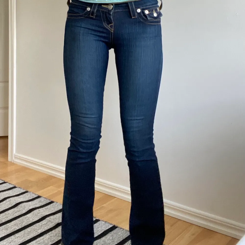 Coola lågmidjade bootcut jeans från True Religion med en mörkare ton, storlek 23 som passar perfekt på mig och jag är 174 cm. Innerbenslängden är ca 83 cm och midjemåttet ca 73 cm! Inte säker att jag vill sälja så kom med bra bud💕Köparen står för eventuell frakt. Jeans & Byxor.