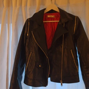 Skinnjacka från Mango - Cool skinnjacka från mango med röd insida och fina dragkjedsdetaljer. Storlek S. Köparen står för frakten. 