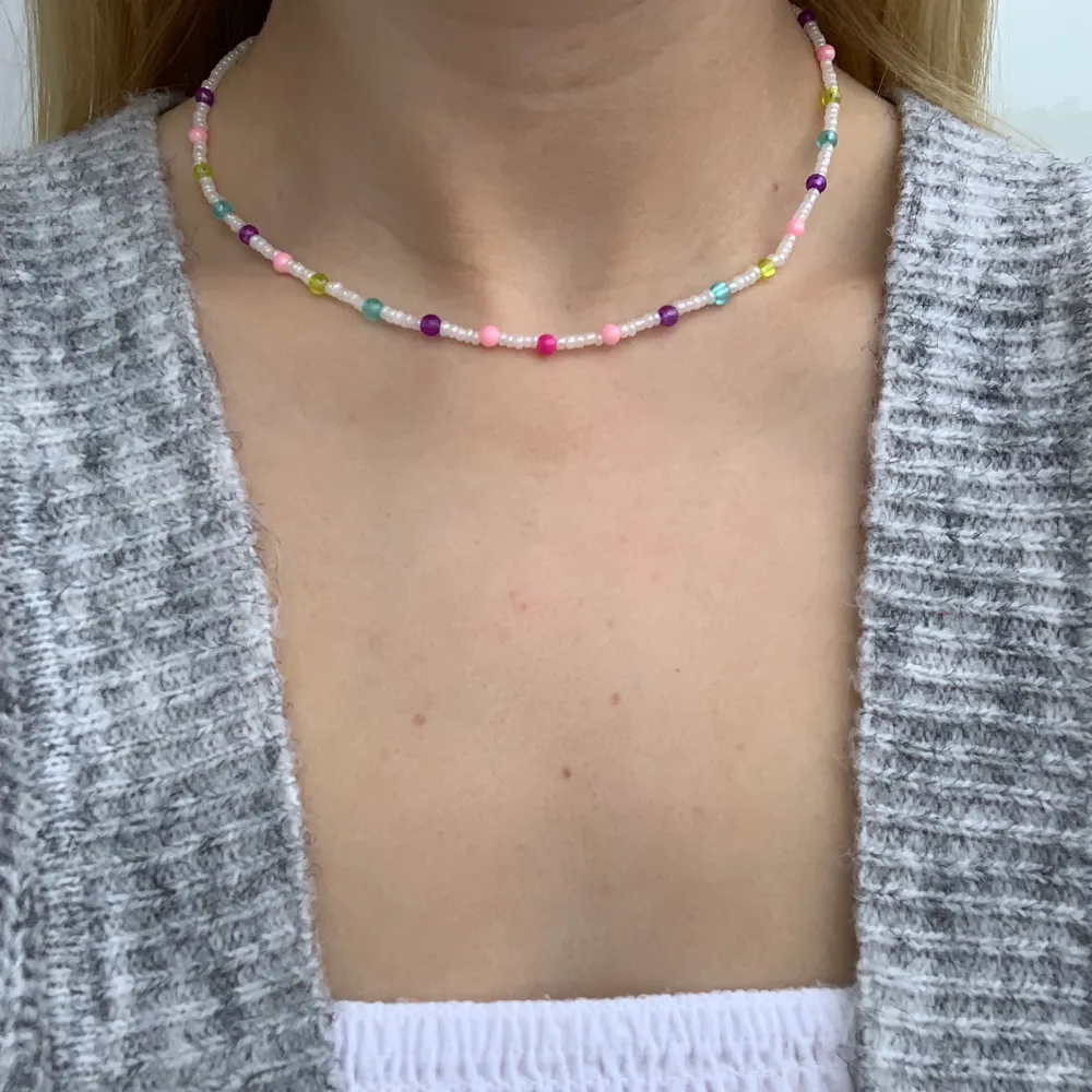 Vitt pärlhalsband med flerfärgade pärlor🤍💜💞🦋🥳 halsbandet försluts med lås och tråden är elastisk . Accessoarer.