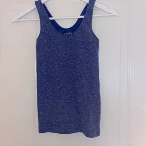 Glittrig blå top - Super glittrig blå, stretchig top! Köpt i new york på ”poof” i storlek s/m men är så stretchig så jag som vanligtvis har xs kan ha den! Använd 1-2 ggr! Frakt ingår i pris!