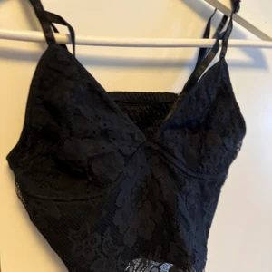 Svart topp/linne  - Festligt svart linne/topp som ej kommer till användning. Fina detaljer vid bröstet. 